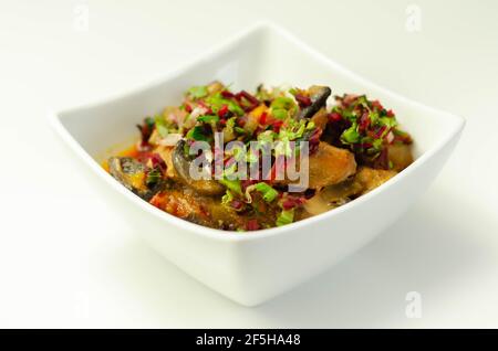 Un stufato di carne, patate, funghi e un mix di peperoni serviti in una ciotola bianca, pasto delizioso Foto Stock