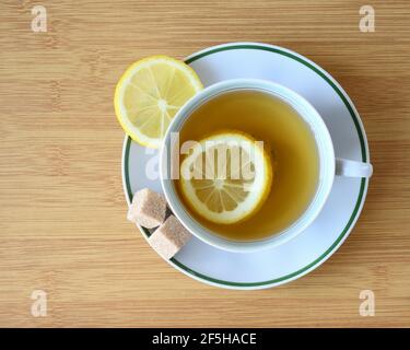 Tazza di tè verde con fette di limone e pezzi di zucchero vista sul tavolo. Foto Stock