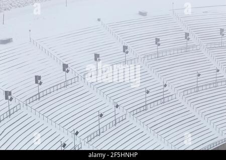 Ampia vista orizzontale dello stadio all'aperto innevato vuoto si trova all'interno di una struttura sportiva invernale, durante una fredda giornata di nebbia Foto Stock