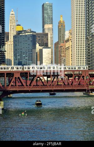 Chicago, Illinois, Stati Uniti. Un paio di treni veloci CTA Brown Line attraversano il fiume Chicago sopra una varietà di traffico sul fiume. Foto Stock