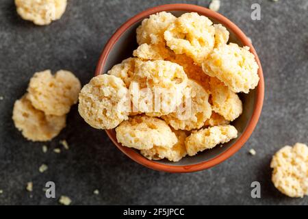 Il formaggio cotto al forno si morde in una tazza di terracotta su sfondo scuro. Questi deliziosi spuntini croccanti sono buoni per il nibble anche per il sapore aggiunto in sou Foto Stock