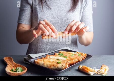 Una donna caucasica sta mangiando il tradizionale Sigara boregi, un rotolo di pasta di pasta di fillo turco fatto con formaggio o ripieno di carne e servito con pars fresco Foto Stock