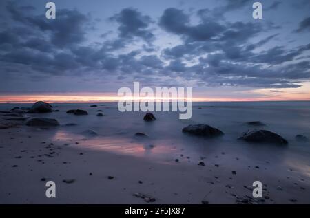 Bel tramonto dopo una giornata estiva fotografata con lunga esposizione, rocce in acqua Foto Stock