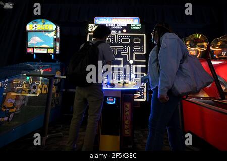 New York, Stati Uniti. 26 Marzo 2021. Persone che giocano un gioco arcade PAC-Man su un grande schermo all'interno della sala di intrattenimento di Dave & Buster a Times Square, mentre l'intrattenimento al coperto riprende al 25% di capacità a New York, NY, 26 marzo 2021. I centri di intrattenimento per famiglie al coperto e i luoghi di divertimento sono autorizzati a riaprire in questo giorno a una capacità del 25%, un adeguato filtraggio dell'aria e seguire i protocolli di pulizia. (Foto di Anthony Behar/Sipa USA) Credit: Sipa USA/Alamy Live News Foto Stock