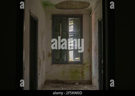 All'interno di un edificio buio abbandonato, le uniche poche luci si accendono attraverso la finestra Foto Stock