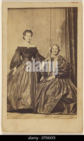 Due donne non identificate: Donna più giovane in piedi, donna più anziana seduta. Photographische compagnie Foto Stock