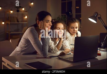 Sorridi madre figlia gemelle guardando video cartoon su laptop prima ora di coricarsi Foto Stock