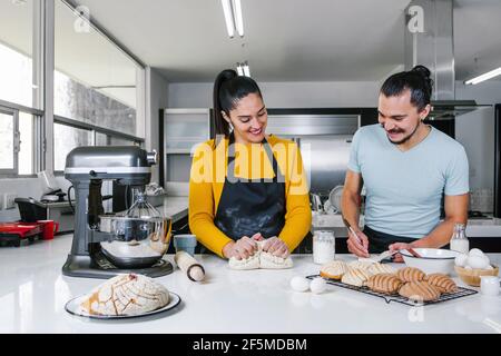 panettieri di coppia latina preparare l'impasto per la cottura del pane messicano chiamato Conchas in cucina a Città del Messico Foto Stock