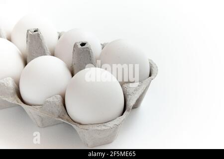 Uova fresche di zenzero confezionate in un contenitore grigio di carta ecologica su sfondo bianco. Foto Stock