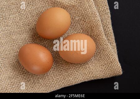 Uova di pollo fresche sul sacco di burlap. Vista dall'alto, disposizione piatta. Foto Stock