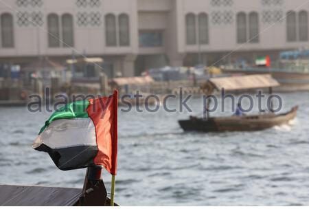 La bandiera degli Emirati Arabi Uniti soffia nel vento su un tratto Di acqua a Dubai Foto Stock