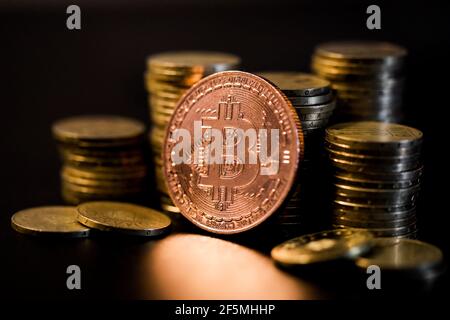Immagine della profondità di campo poco profonda (fuoco selettivo) con una moneta di metallo di Bitcoin vicino ad altre monete metalliche - concetto di criptovaluta. Foto Stock