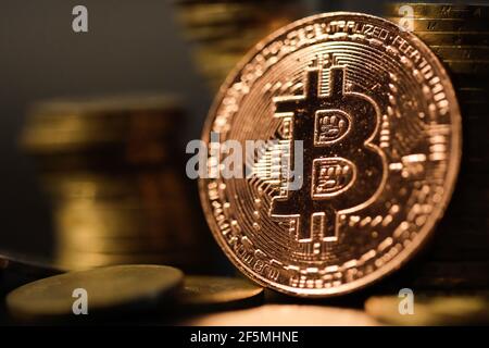 Immagine della profondità di campo poco profonda (fuoco selettivo) con una moneta di metallo di Bitcoin vicino ad altre monete metalliche - concetto di criptovaluta. Foto Stock