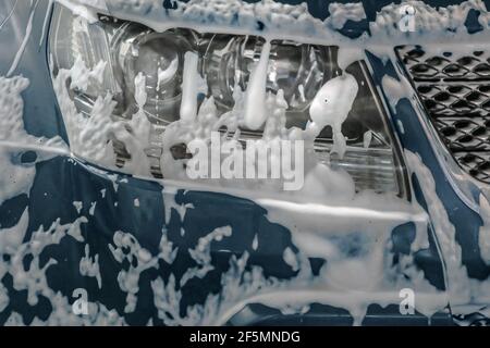Autolavaggio. Schiuma di shampoo sul paraurti dell'auto. Foto Stock