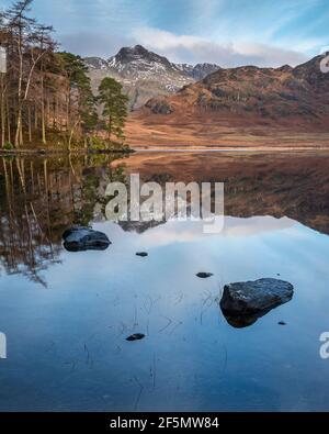 Bella alba invernale su Blea Tarn nel Lake District con Pikes Langdale innevate in lontananza Foto Stock