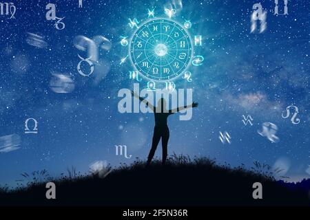 Segni zodiacali astrologici all'interno del cerchio dell'oroscopo. Illustrazione della silhouette della donna che consulta le stelle e la luna sulla ruota dello zodiaco. Foto Stock