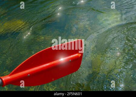 Pagaia rossa per rafting e kayak con attrazioni e sequine sull'acqua. Tonato. Foto Stock