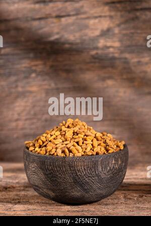 Semi di fenugreek organici in ciotola di legno - Trigonella foenum - graecum Foto Stock