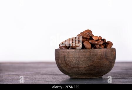 Chicchi di caffè appena tostati in una piccola ciotola di legno Foto Stock