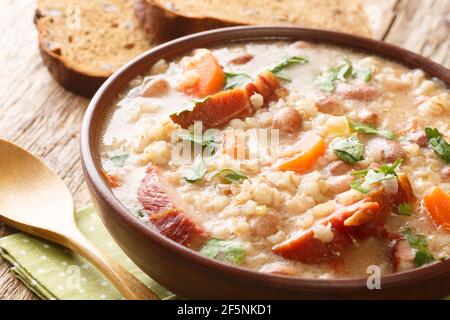 Zuppa ricca di orzo e fagioli con carne affumicata e verdure primo piano in una ciotola sul tavolo. Orizzontale Foto Stock