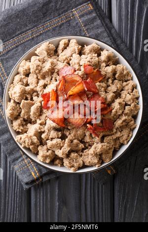 Ajdovi zganci piatto nazionale sloveno di farina di grano saraceno e pancetta fritta primo piano in una ciotola sul tavolo. Vista dall'alto verticale Foto Stock