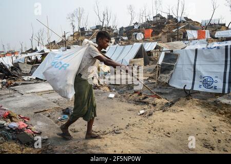 Un uomo porta i resti incantati dei suoi effetti personali a un Sito di rifugi temporanei per rifugiati Rohingya sfollati giorni dopo un incendio a un rifugiato Foto Stock