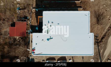 Vista aerea di un edificio di appartamenti con tetto piano in costruzione, sistema zavorrato con membrana geotessile, PVC o EPDM Foto Stock