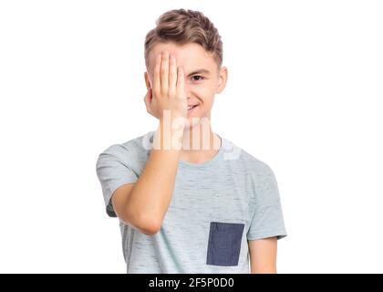 Bel ragazzo si guarda con un occhio mentre gli copre l'altro occhio con la mano, isolato su sfondo bianco Foto Stock