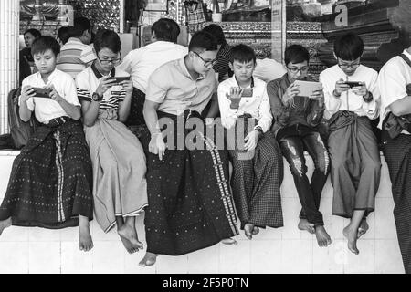 Giovani adolescenti birmano giocando con i loro telefoni cellulari alla Shwedagon pagoda Yangon, Myanmar. Foto Stock