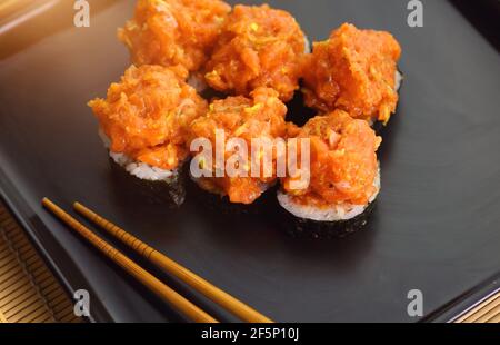 appetitoso sushi tartare di pesce servito piacevolmente su un piatto nero Foto Stock