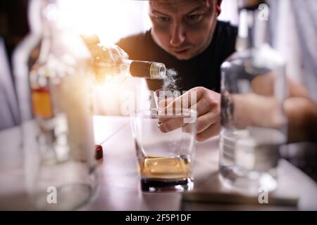 l'uomo con un problema di alcool beve l'alcool da solo in un den Foto Stock