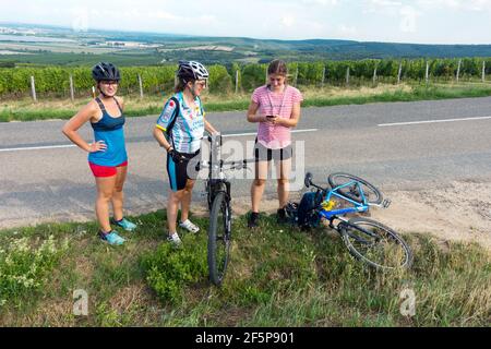 Tre giovani donne in bicicletta si riposano vicino alla bici sulla strada Foto Stock