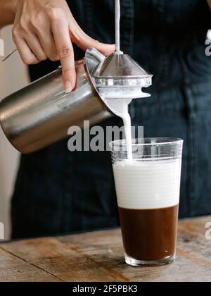 Barista che crea un delizioso caffè con latte Foto Stock