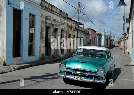 Un'auto verde d'epoca timorosa parcheggiata su una strada stretta, una mostra di tipici contrasti cubani tra l'architettura vecchia e le auto di lusso Foto Stock