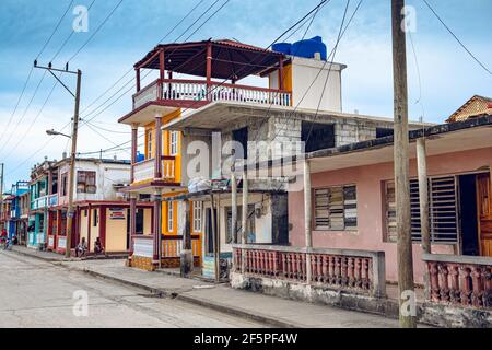 Baracoa, Cuba - 25 ottobre 2019: Vecchio cubano di fronte al suo alloggio (casa Particular) a Baracoa con propaganda comunista dipinta e che Foto Stock