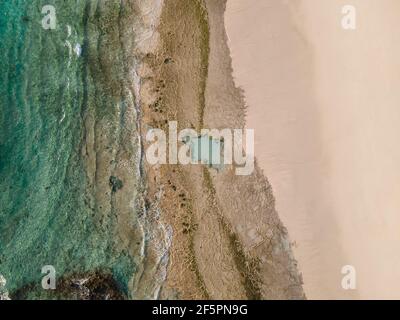 Spiaggia sabbiosa e rocciosa di fondo foto aerea. Sabbia bianca, acque turchesi cristal e barriera corallina Foto Stock