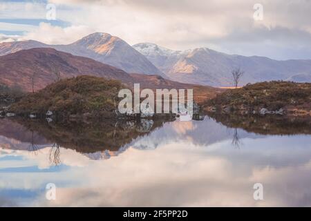 Un suggestivo paesaggio montano che si riflette su un tranquillo e tranquillo lago di Rannoch Moor, vicino a Glencoe, nelle Highlands scozzesi, Scozia. Foto Stock