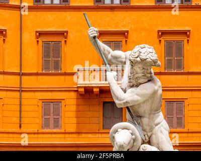 Nettuno a Roma. Una magnifica statua del mitico dio del mare, contro una classica facciata arancione di una residenza urbana. Foto Stock