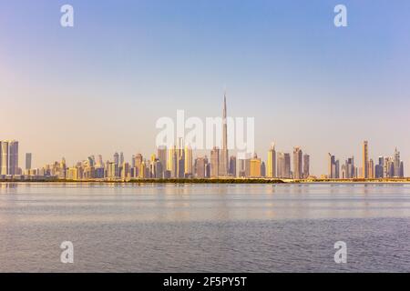 Il paesaggio dello skyline del centro di Dubai con riflessi nel Dubai Creek, caldi colori dorati, visti dalla passeggiata del Dubai Creek Harbour. Foto Stock