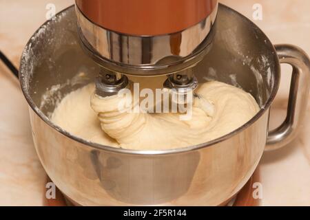 Impastare l'impasto in un mixer elettrico. Preparare l'impasto a casa per la cottura in un mixer Foto Stock