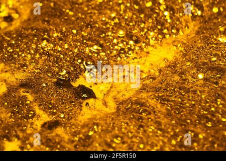 Oro bollente. La consistenza della schiuma come sfondo. Concetto di sfondo e texture. Primo piano di schiuma dorata gorgogliante Foto Stock