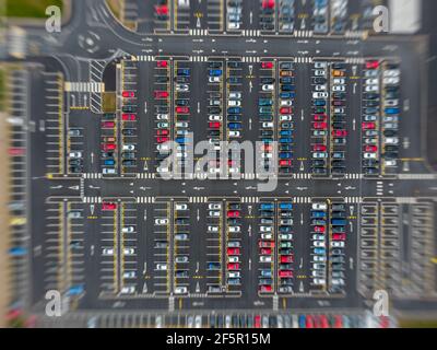 Lo zoom in movimento sfoca molte vetture grande parcheggio moderno con strade simmetriche file di parcheggi molto simmetriche e colori vista aerea sopra Foto Stock