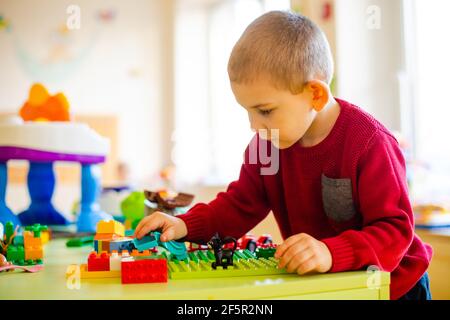 Il ragazzo prescolare immerso in un gioco con un costruttore Foto Stock