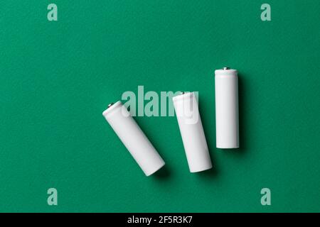 Batterie ricaricabili AAA bianche su sfondo verde. Posiziona per il testo. Concetto di energia verde. Foto Stock
