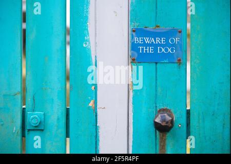 Attenzione al segno del cane sul cancello blu della casa di legno Foto Stock