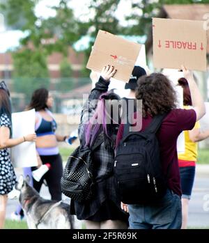 Giovani che partecipano a una protesta silenziosa e pacifica lungo la strada con cartelli e manifesti di cartone Foto Stock
