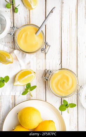 Deliziosa cagliata di limone fatta in casa decorata con frutta fresca un vaso di vetro su rustico sfondo di legno Foto Stock