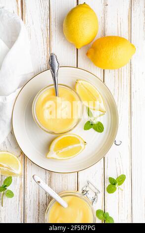 Deliziosa cagliata di limone fatta in casa decorata con frutta fresca un vaso di vetro su rustico sfondo di legno Foto Stock