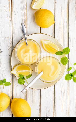 Deliziosa cagliata di limone fatta in casa decorata con frutta fresca un vaso di vetro su rustico sfondo di legno Foto Stock