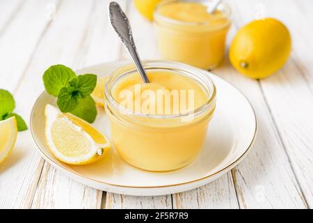 Deliziosa cagliata di limone fatta in casa decorata con frutta fresca un vaso di vetro su rustico sfondo di legno Foto Stock